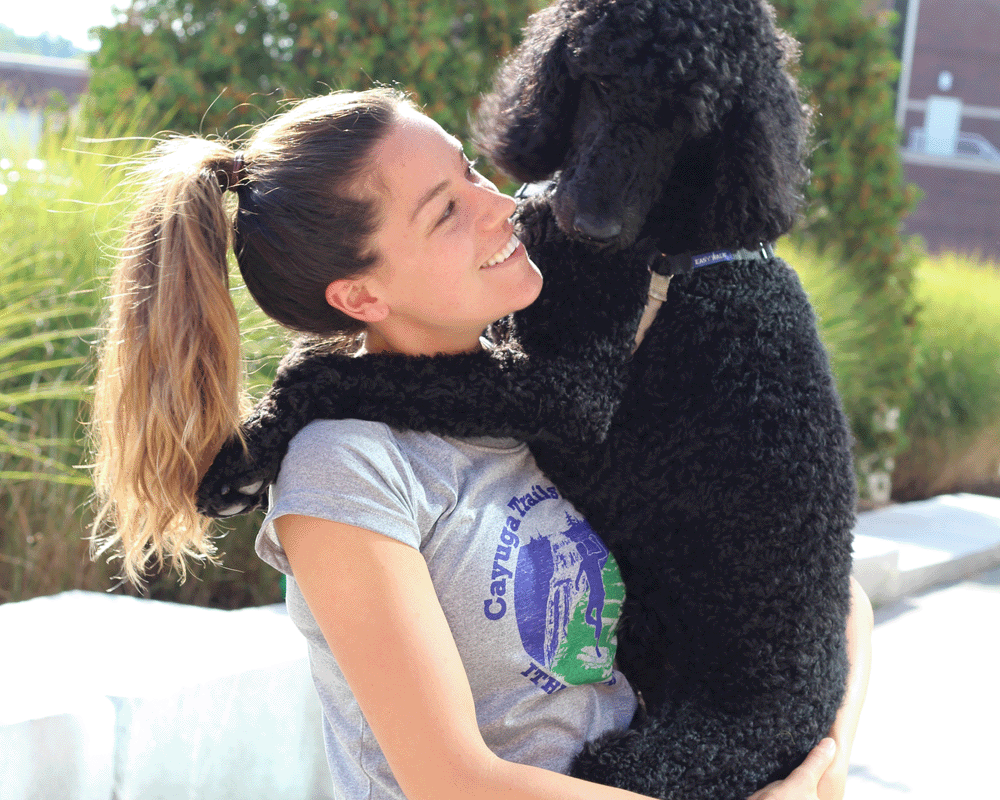Employee outdoors with dog in her arms
